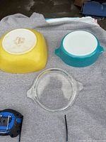Bottom views of yellow square dish, blue round dish, and clear lid
