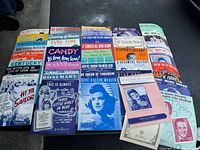 Group view of numerous sheet music covers spread on surface