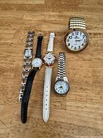 All five wristwatches laid out on surface