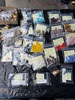 Overview of lot showing many zip bags of colored beads and box of natural beads