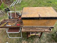 Overall view of mustard yellow wooden toolbox with sliding drawer showing tools