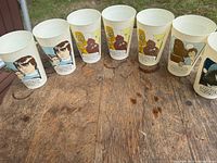 Seven cups lined on table showing character graphics