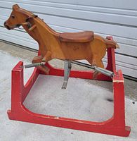 Side view of wooden rocking horse on red spring frame