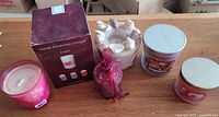 Six assorted candles including boxed color-changing candle, glass jar candle, votive in bag, cherub holder candle, Yankee Candle jar, pink tin candle