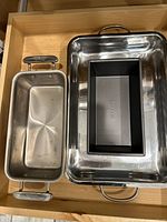 Top view of stainless roasting pan, stainless loaf pan, and black non-stick loaf pan
