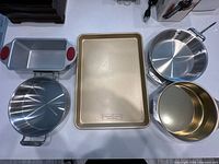 All six pieces laid out: loaf pan, frying pan, baking sheet, stock pan, two nested cake pans