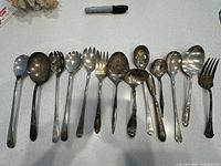 Full set of 14 assorted vintage serving utensils laid out in a row