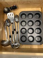 Utensils, measuring-cup set and muffin pan inside drawer