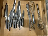 Knives, tongs and whisks arranged in drawer