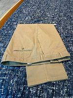 Full view of khaki Dockers dress pants folded on surface