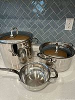 All three stainless steel pots with two lids displayed on countertop