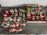 Group of wooden figure ornaments and two boxes of fruit ornaments on table