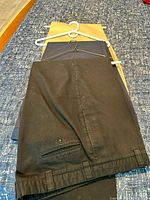 Three pairs of folded pants on hangers showing colors