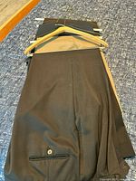 Stack of three pairs trousers on hanger showing colors and cuffs