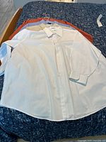 Four shirts stacked on bed showing colors