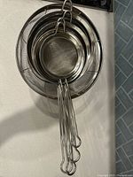 Nested handled strainers hanging together