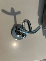 Front angle of chrome double hook on round base