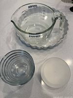 Group shot showing measuring cup, white quiche dish, ribbed bowls and lid