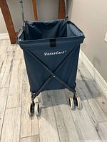 Front view of dark blue VersaCart showing bag, frame X-braces and double wheels