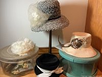 Group shot showing four hats, hat stand, two boxes