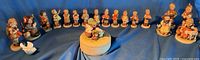 Full semicircle view of 16 Hummel figurines, trinket box and dove