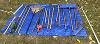 All long-handled yard tools laid on blue tarp