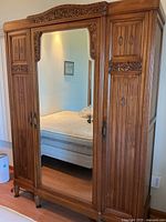 Full front view showing mirrored center door, carved details, overall condition