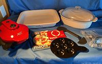 All pieces laid out: rectangular Cornflower casserole, oval casserole with glass lid, Redi-Set-Go cooker, insert tray, spatulas, booklets, accessory bags