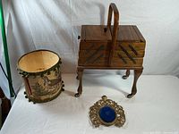 Overview of sewing box on legs, fabric pheasant bin, ornate brass frame with blue center