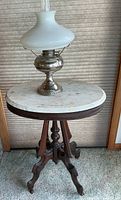 Full view of marble-top table with oil lamp placed on top