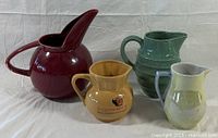 Group shot of four ceramic pitchers showing size and color