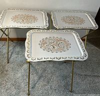 Three matching folding tray tables standing on carpet, showing tops and legs