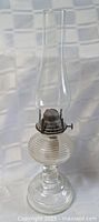 Full view of clear glass oil lamp with chimney
