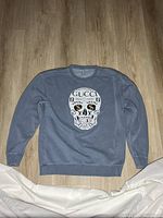 Full view of blue-grey sweatshirt laid flat showing entire garment