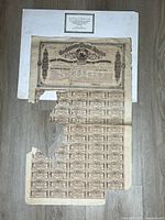 Top view of damaged Confederate bond with coupons and COA above