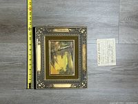 Framed painting with tape measure and certificate visible
