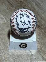 Front view of autographed baseball on Athletics stand showing multiple signatures