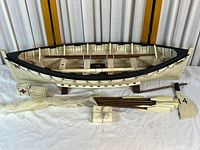 Full view of lifeboat on stand with oars, crates, canvas
