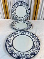 Front view of three identical ornate blue & white dinner plates