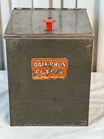 Front view showing tin, lid with red knob, label