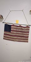 Full view of quilted American flag hanging on wall with rod and cord
