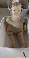 Full view of doll lying in tub showing overall condition