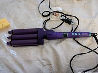 Curling iron laid out showing barrels, handle, cord and controls