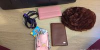All items laid out: faux fur hat, pink wallet, brown wallet, coin purse with tag, two lanyards