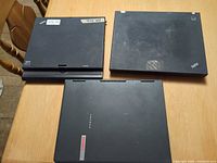 Three closed laptops on table, showing lids and logos