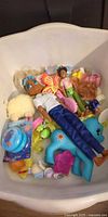 Assorted dolls and toys inside white tub