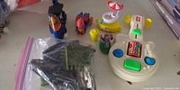 Entire lot showing Busy Guitar, two vehicles, carousel boat, robot figure, bag of parts