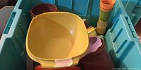 Plastic tote containing yellow square bowl and assorted multicolour Tupperware pieces
