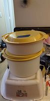 Two stacked Tupperware round containers with yellow lids
