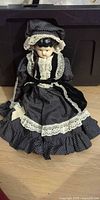 Front view of porcelain head doll seated in full outfit